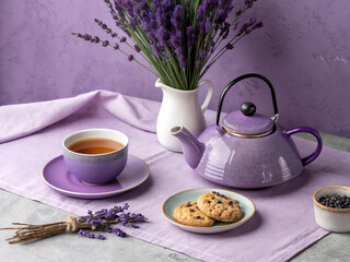 features a purple tea set on a lilac tablecloth, accompanied by lavender cookies, a vase of lavender flowers, and a small bowl of lavender buds.