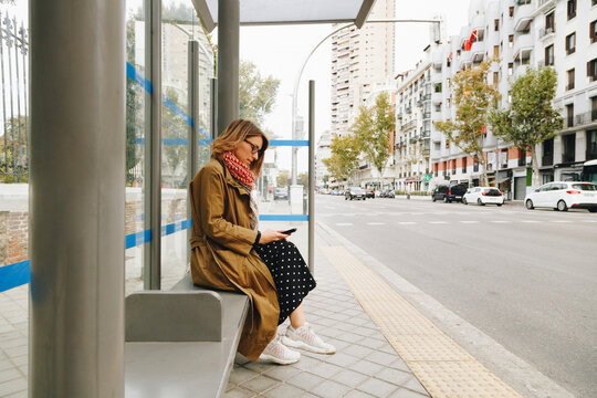 Woman using smart phone at bus stop