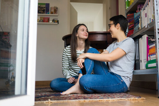 Two girlfriends at home, sitting on floor, talking