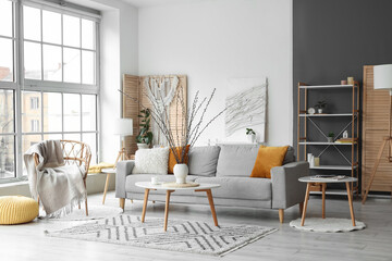 Interior of living room with sofa, armchair and willow branches in vase