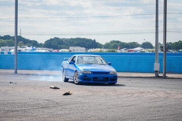 Blue sports car drifting on racetrack. © Wirestock