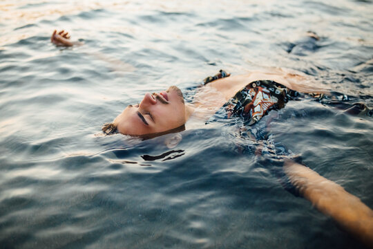 Young man with eyes closed wearing unbuttoned shirt while floating in water