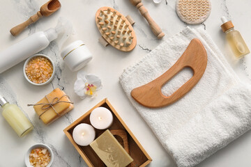 Composition with wooden guasha body massage tool, towel and candles on marble background