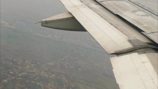 Aerial view from airplane window. Wing and plaps in flight over rural landscape.
