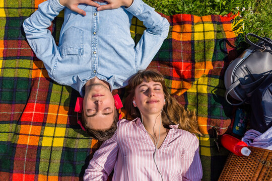 Young couple relaxing on in a park, listening music with headphones