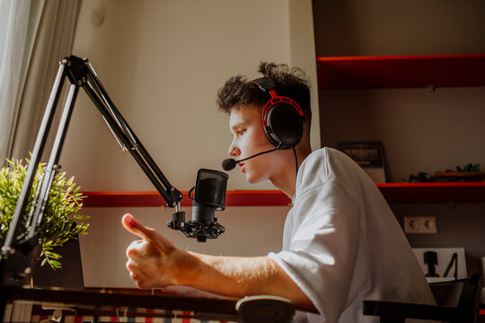 Teenage boy podcasting and gesturing in front of laptop at home