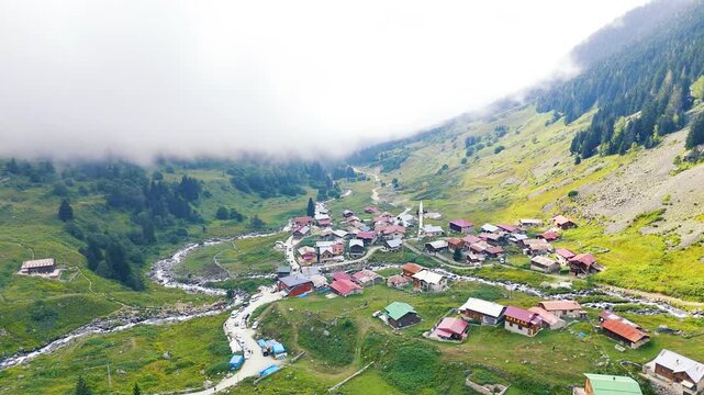 Aerial view of Elevit Highland nestled in the valley of Camlihemin, Rize, Turkiye, with fog descending from the surrounding mountains