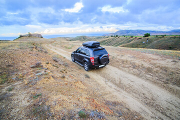 SUV moves along a dirt road to the sea.