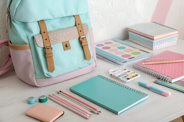 School supplies laid out on a table with a satchel bag, pastel colors, back to school theme.