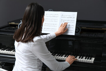 Young woman playing piano with note sheet