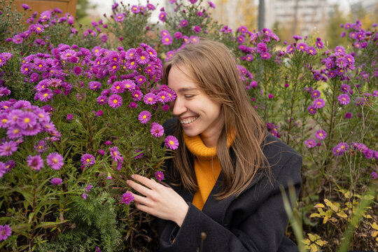 Happy woman near aster flowers in park