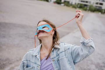 Woman outdoors wearing blue superhero mask expressing freedom and confidence