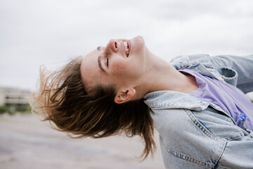 Smiling woman enjoying dancing outside on a rainy day in modern style