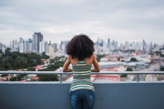 Panama, Panama City, back view of young woman standing on balcony looking at view