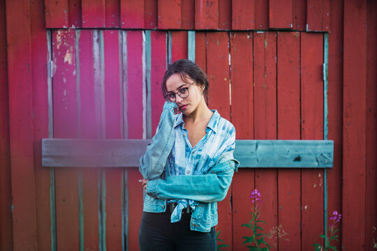 Portrait of a young woman standing in front of a red wood hut