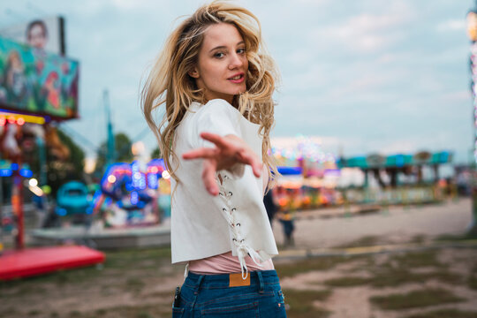 Young woman on a funfair reaching out her hand