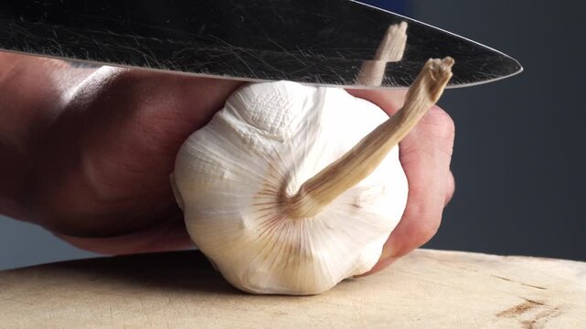 Person cutting a bunch of garlic in half. Close-up