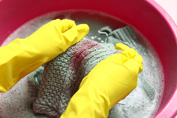 Woman in rubber gloves washing clothes in plastic basin, closeup