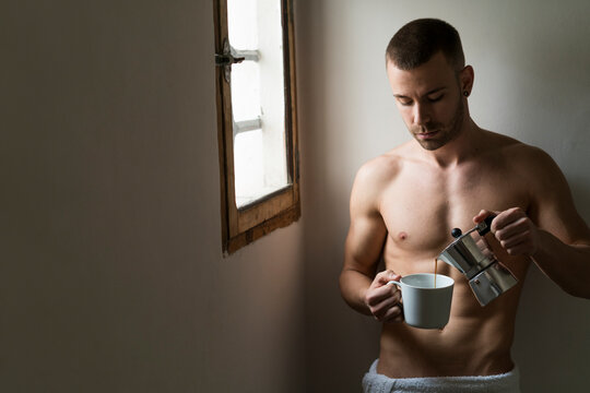 Attractive young amn with six pack drinking coffee