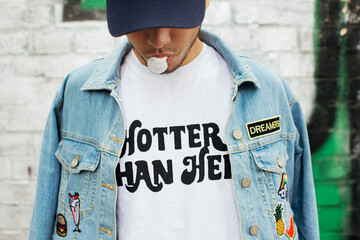 Young man with gum bubble wearing t-shirt with saying 'Hotter Than Hell'