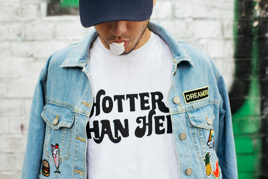 Young man with gum bubble wearing t-shirt with saying 'Hotter Than Hell'
