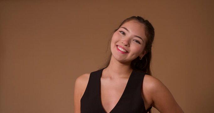  Studio video clip of a young adult female making different expressions, both positive and negative, towards the camera. She has long brunette hair and is wearing smart casual clothing.