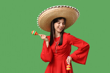 Young woman with sombrero and maracas on green background. Cinco de Mayo celebration