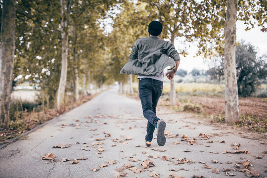 Spain, Tarragona, back view of young man running on autumnal country road