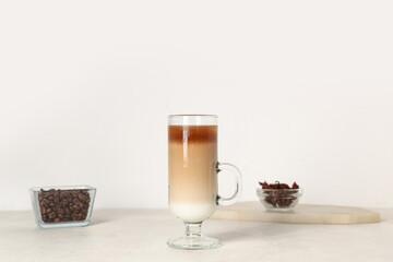 Glass cup of iced latte with star anise and coffee beans on white background