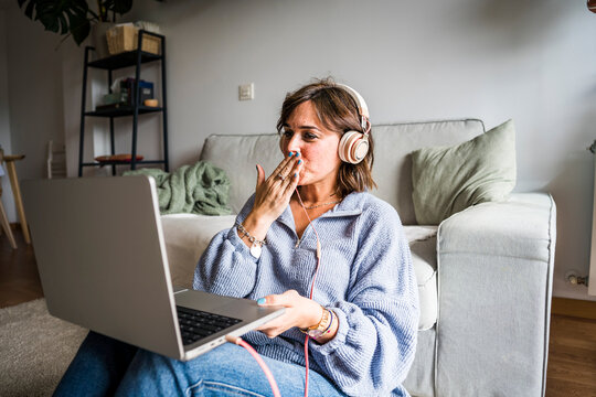 Woman blowing a kiss on video call through laptop in living room