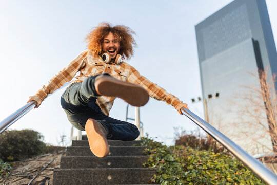 Happy man holding railing and jumping on staircase