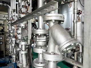 industrial air conditioning. A close-up shot of a complex industrial pipeline system, with multiple large, metallic pipes and flanges, featuring various gauges and connections.