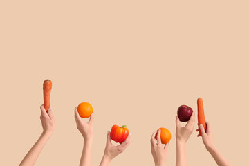 Hands with fresh fruits and vegetables on beige background