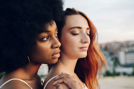 Afro woman looking away while leaning on female friend
