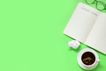 Notebook with text GOALS 2025, cup of coffee and eyeglasses on green background