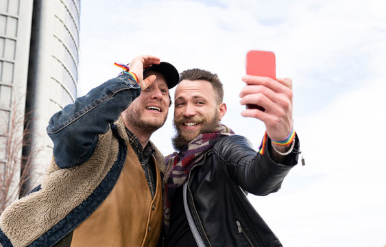 Bearded man taking selfie with boyfriend while standing against sky