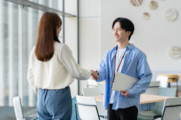 Obraz premium 握手する若いビジネスパーソン「撮影協力：スカパー東京メディアセンター」