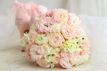 Beautiful wedding bouquet and bride's shoes on light background