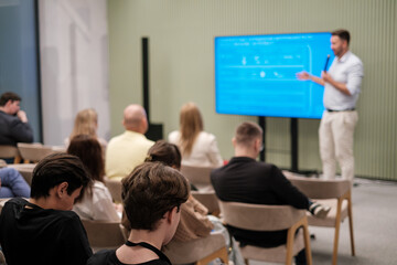Fototapeta na wymiar Audience listening to speaker presenting in a contemporary seminar setting, fostering engagement.