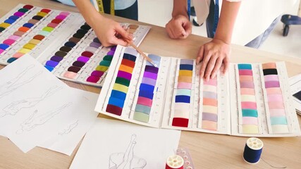 Hands selecting fabric swatches on desk with fashion sketches, thread, and tools. Design studio scene with textile, color palette, samples, tailoring materials, and atelier creativity. - Powered by Adobe