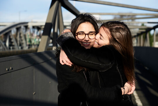 Happy friends hugging each other on a bridge