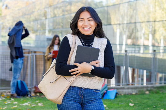 Cheerful woman with tablet PC on university campus