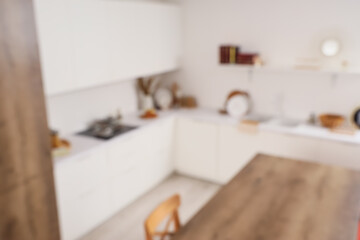 Blurred view of light kitchen with white counters and shelf