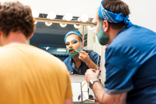 Bearded man doing drag queen makeup by friend