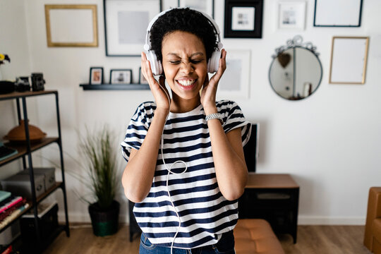 Happy young woman listening to music with headphones at home