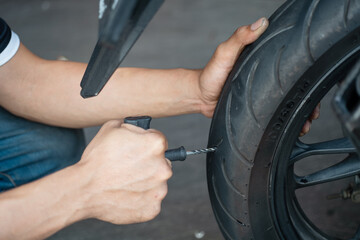 Rider use a tire plug kit or reamer plugger tool and trying to fix a hole in tire's sidewall...