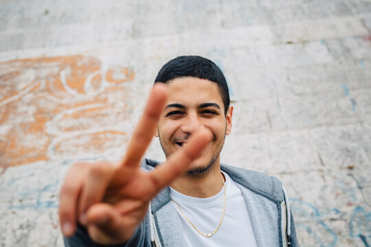 Smiling young man showing victory sign