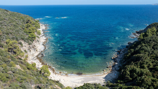 Tranquil scenery of a hidden beach with inviting turquoise waters, surrounded by lush greenery in Toroni, Greece, perfect for a relaxing summer getaway