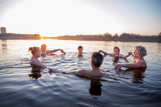 Male and female friends holding hands in water