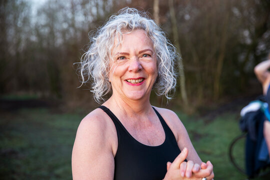 Smiling senior woman with hands clasped in nature